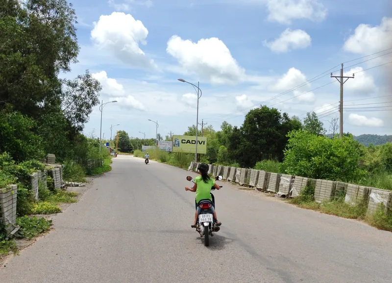 Xe máy và ô tô chạy trên đường ven biển Phú Quốc lúc chiều muộn